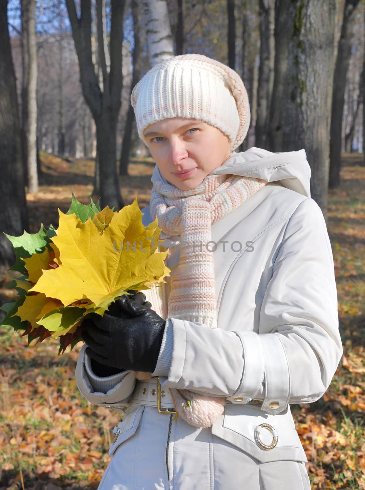 Young woman with a bouquet of maple leaves in an autumn wood 