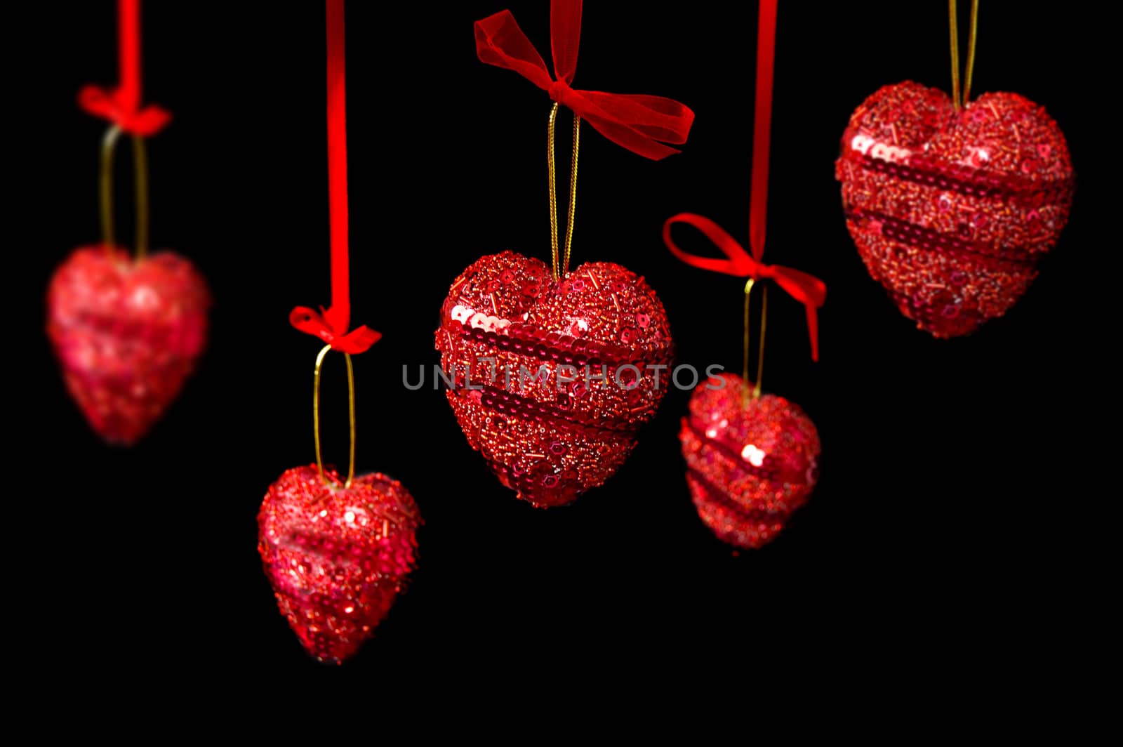 Many red hearts hanging over black, focus on front heart