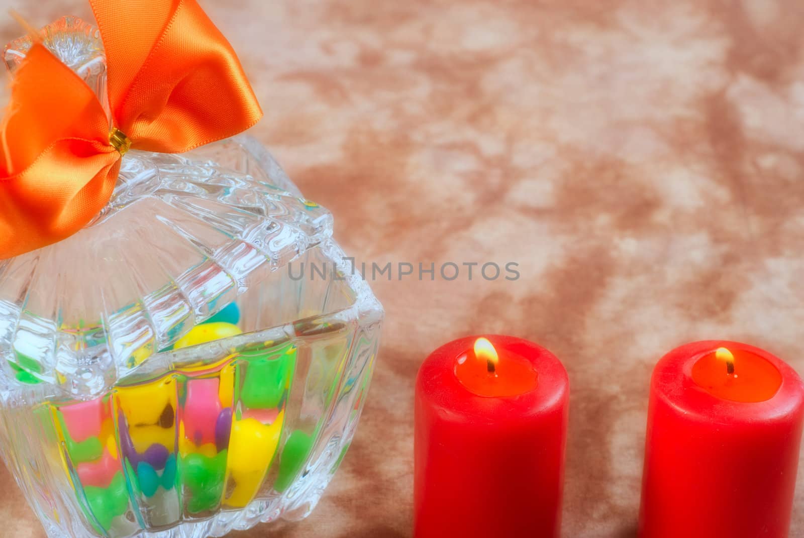 A romantic scene with a glass bowl full of candy with two lit red candles