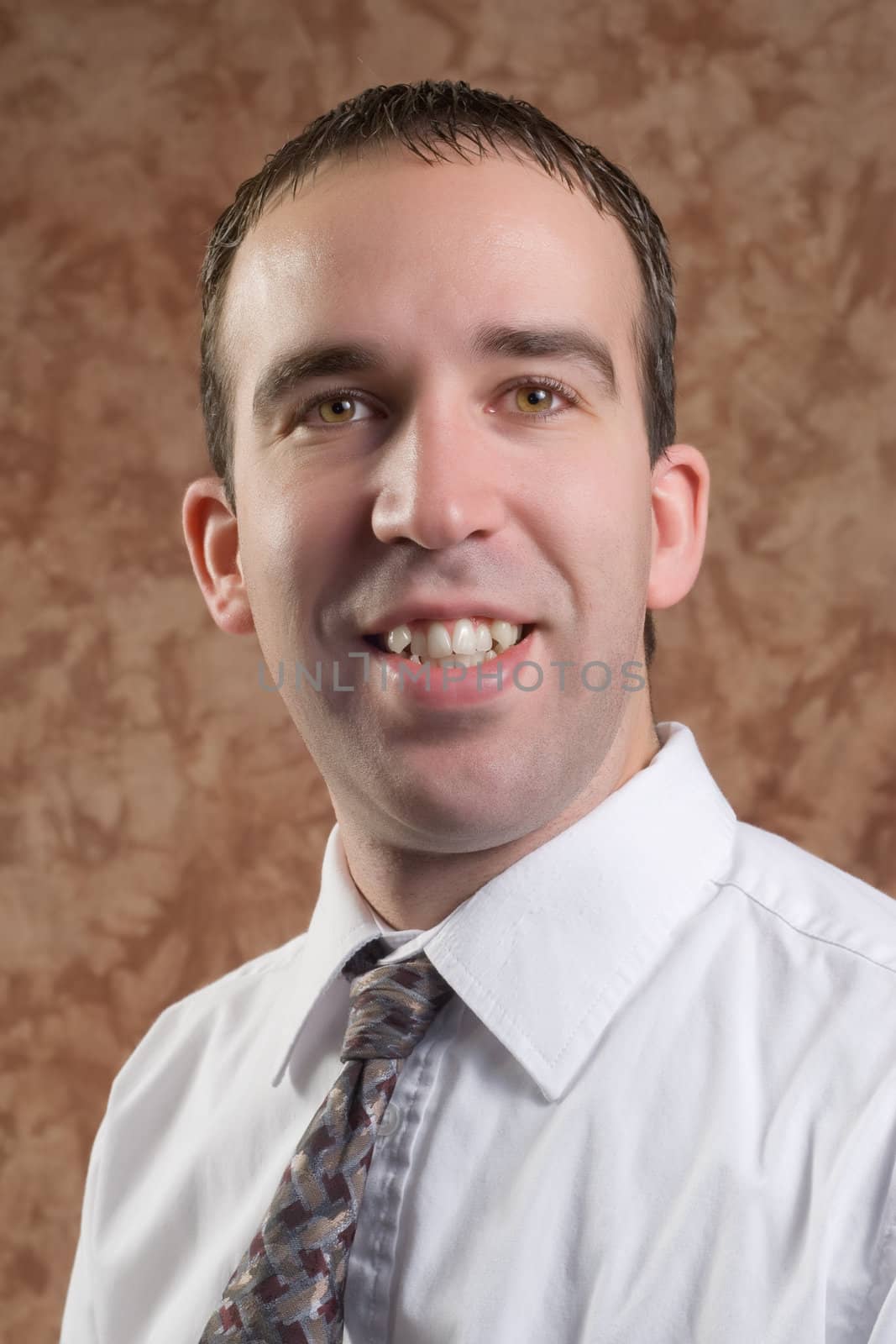 Closeup of a young man wearing a shirt and tie, smiling for his portrait