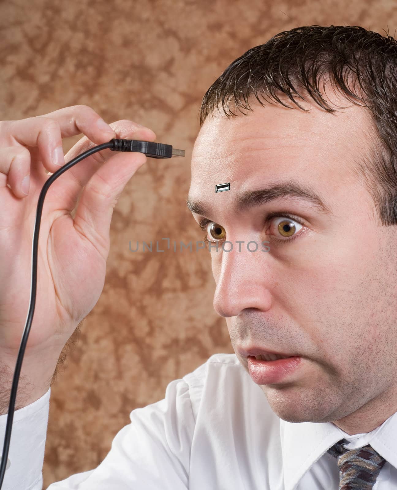 Closeup of a young man about to insert a USB plug into his head