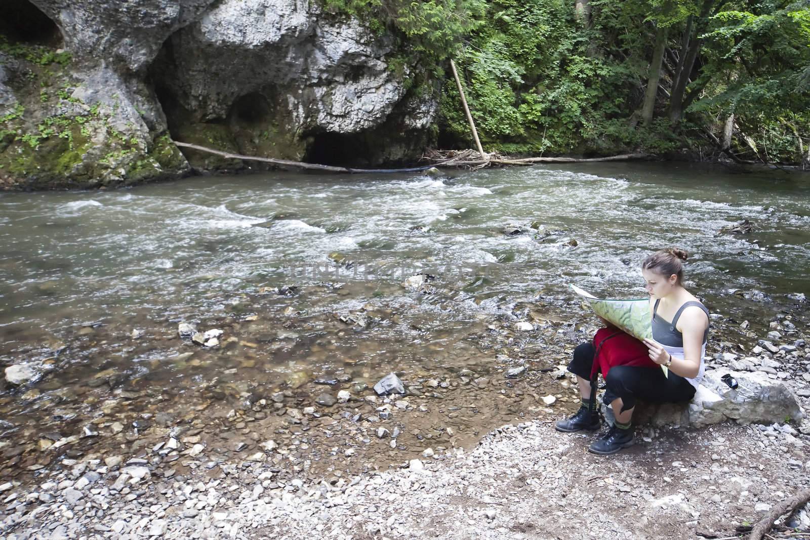 woman reading a map on the bank of mountain river, Slovak Paradise