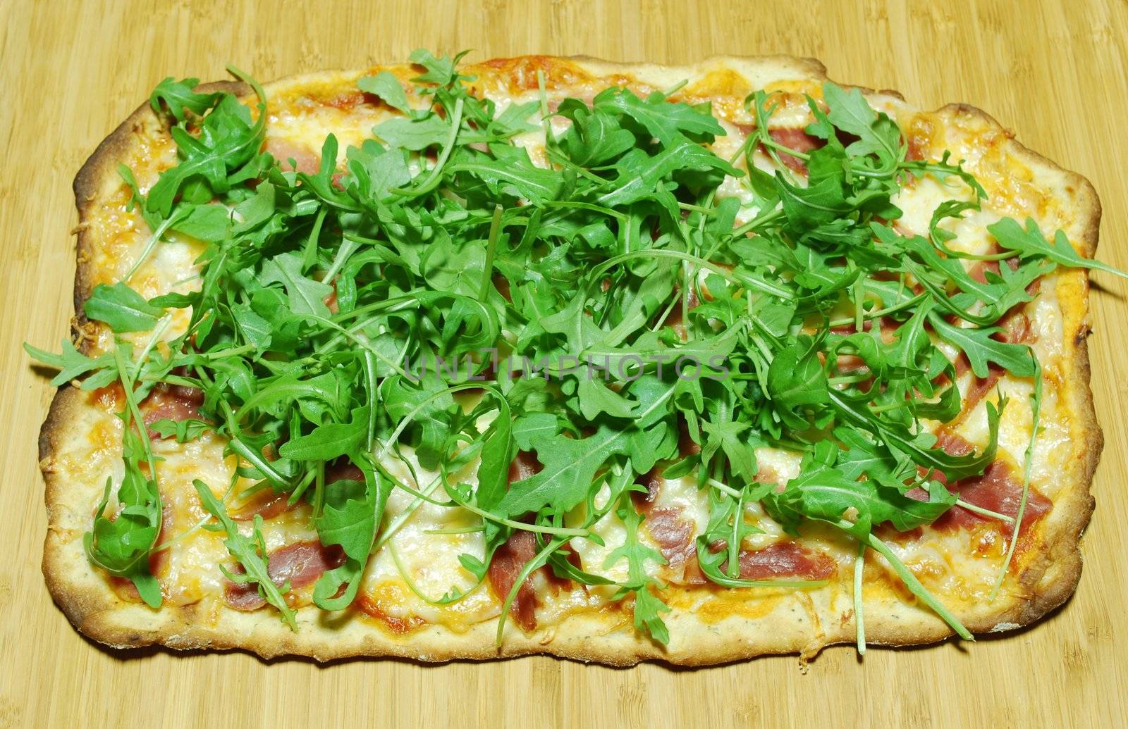 homemade pizza with 3 cheeses with prosciutto and arugula (on wooden board)