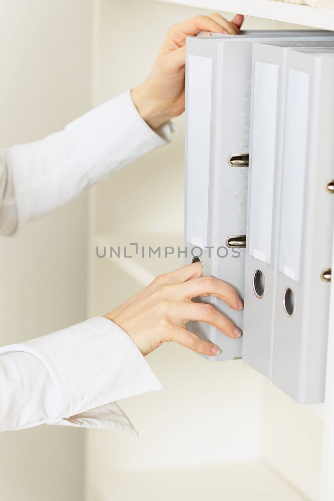 Hands of the official remove from a shelf a folder with classified documents