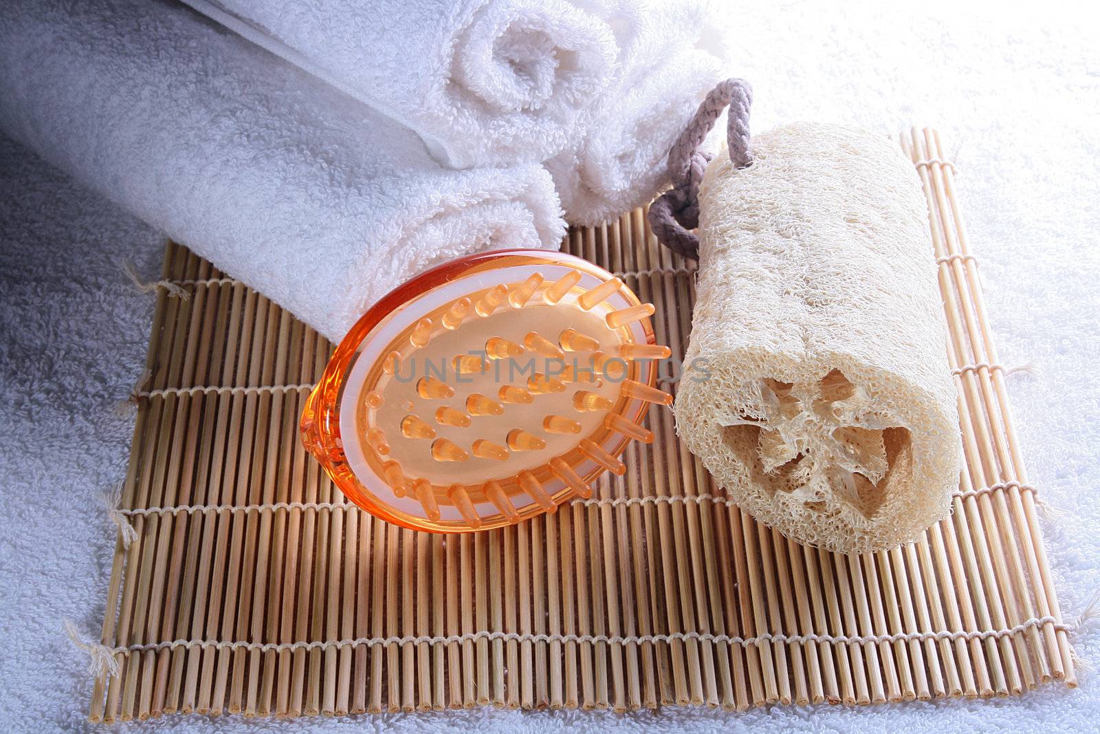 Terry towels with a massage brush and a bast on a laying made of a bamboo.