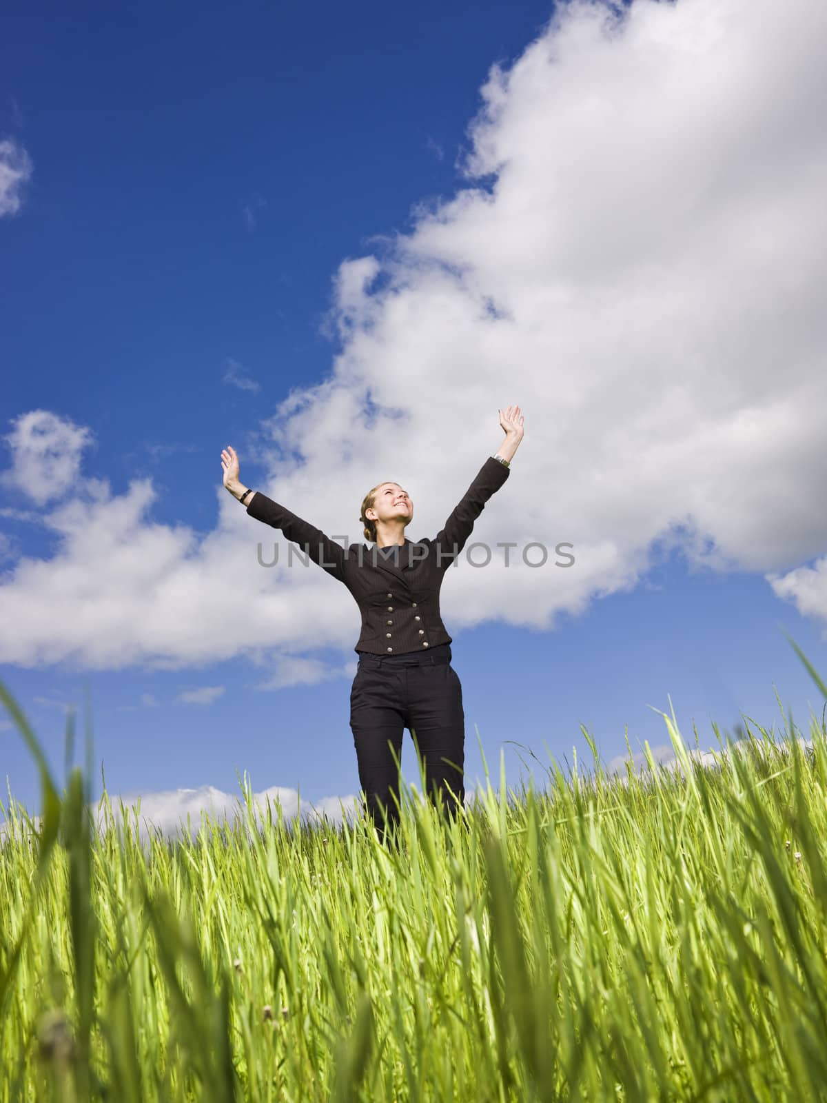 Young woman standing in the grass towards blue sky