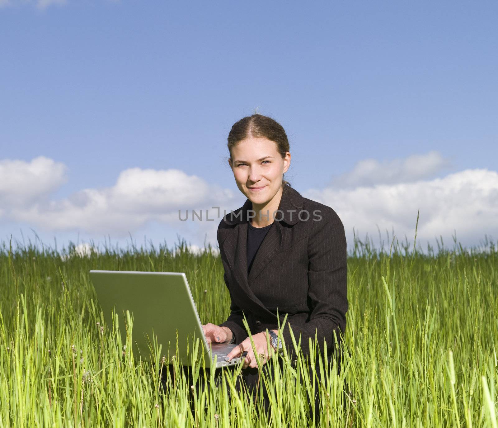 Woman sitting with her laptop in the grass by gemenacom