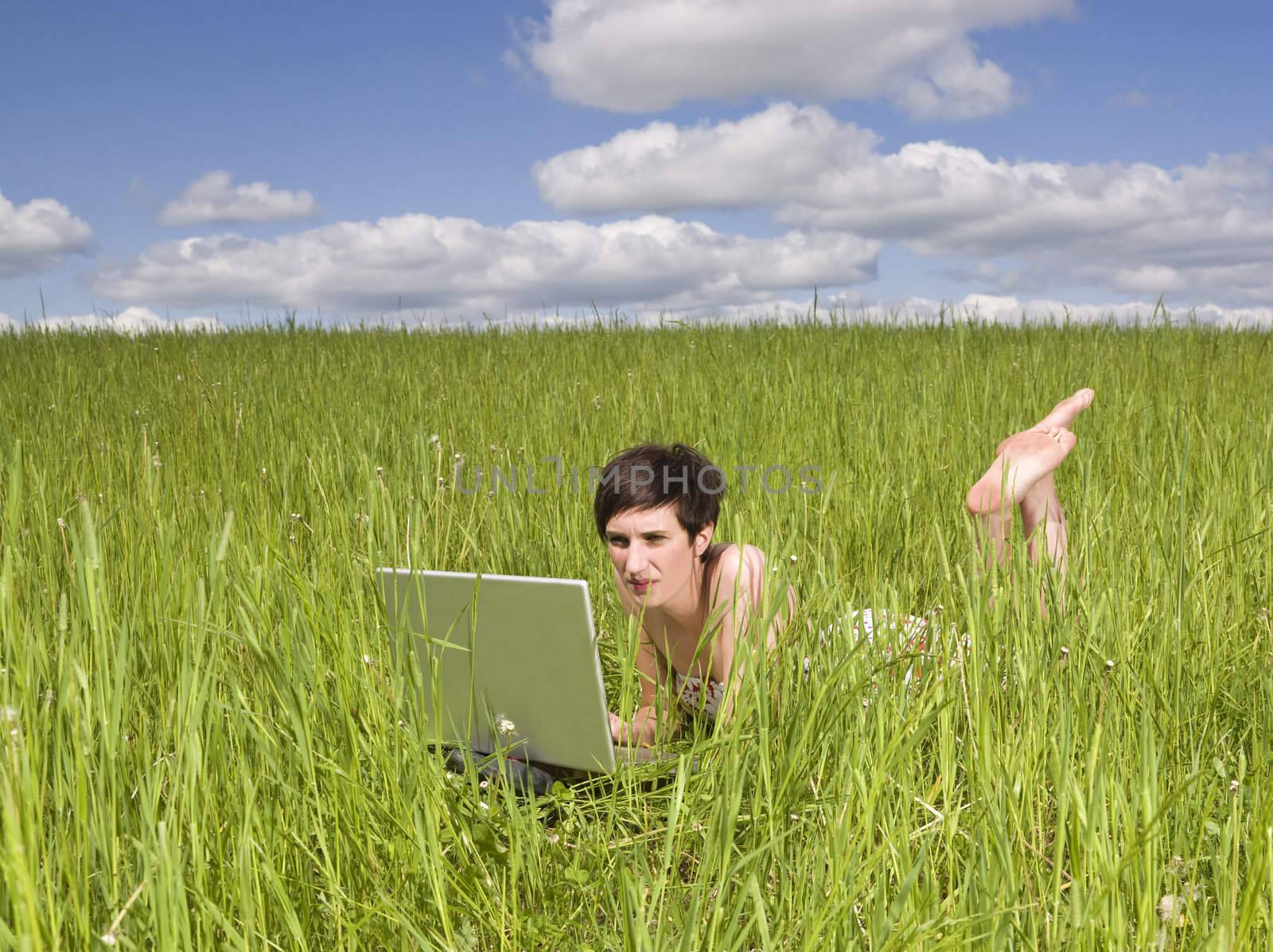 Woman with her computer in the grass