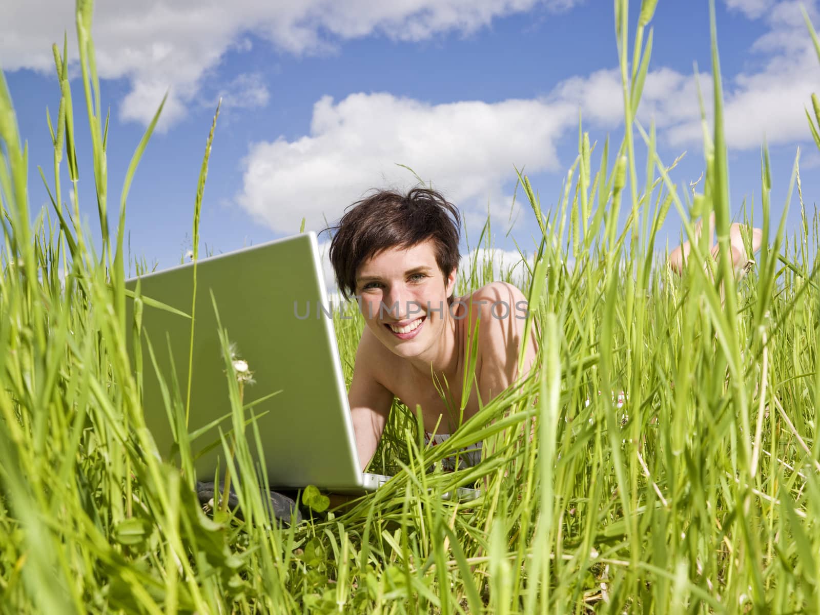 Smiling Woman with her computer in the grass by gemenacom