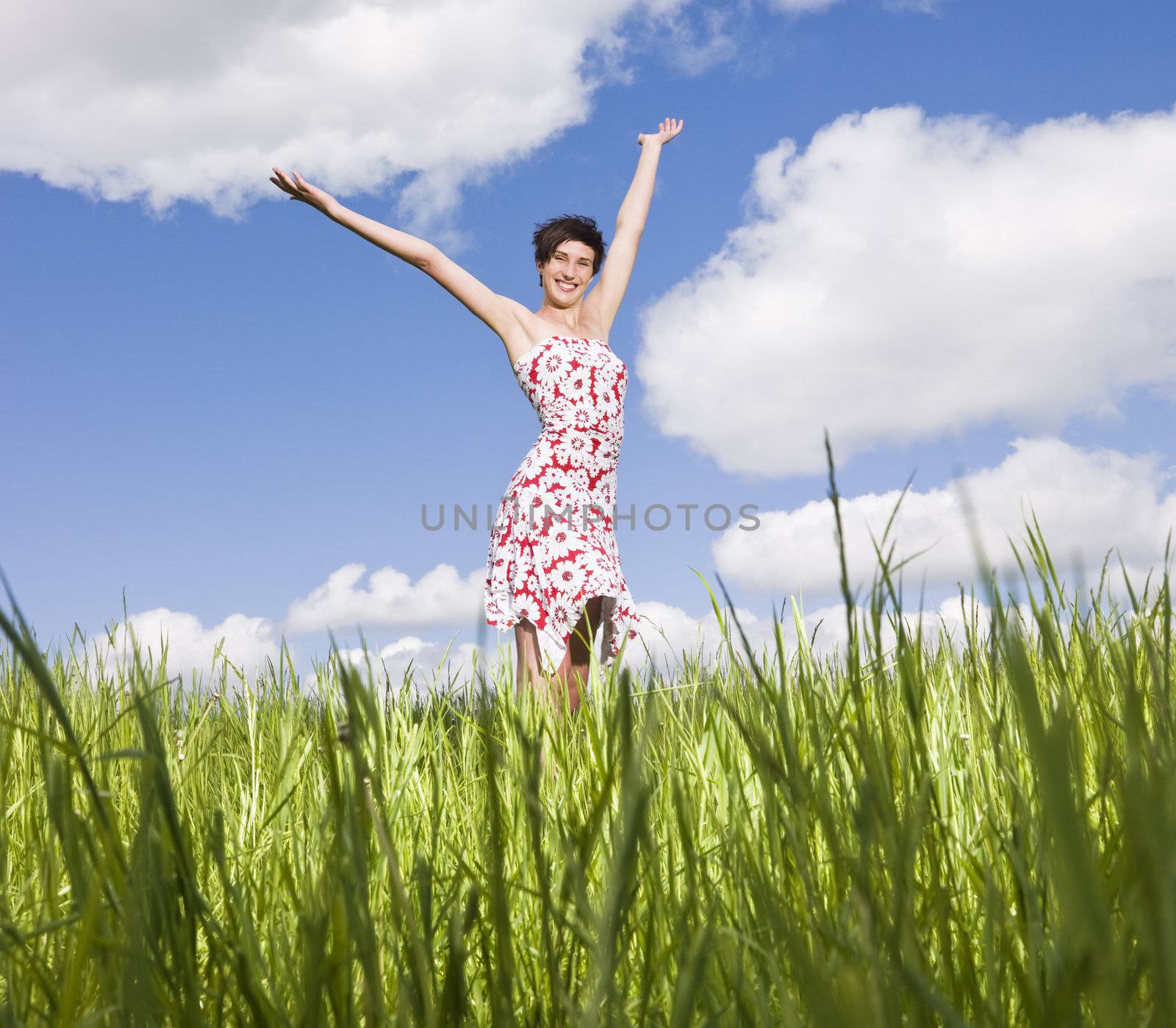 Young woman standing on a field with her arms raised