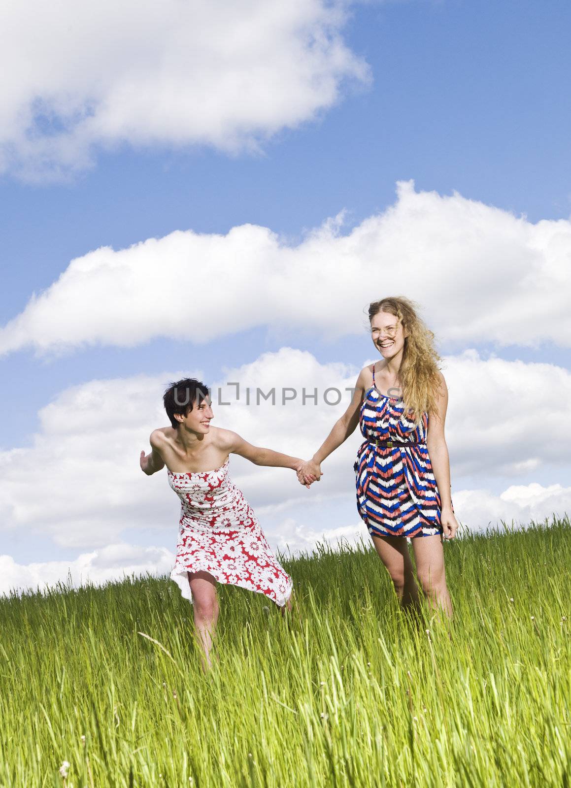 Two women holding hands on a field