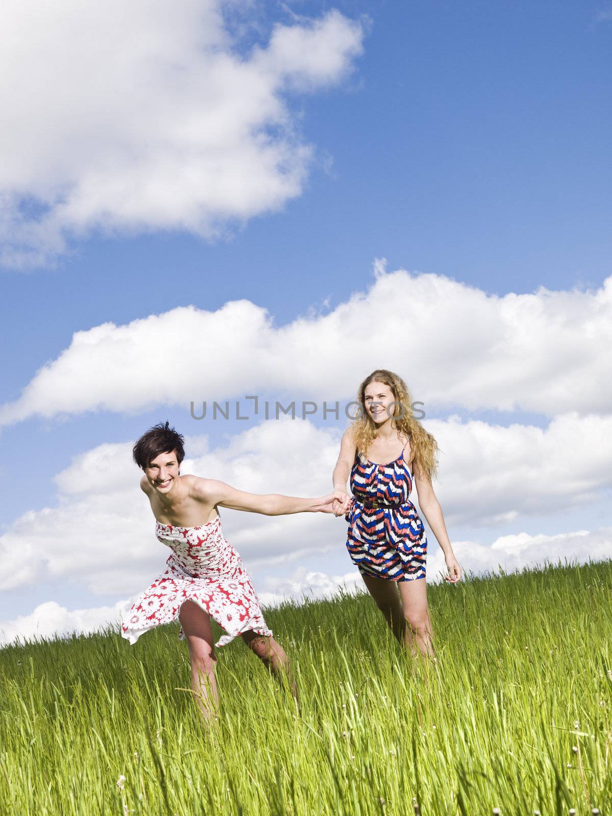 Two women holding hands on a field