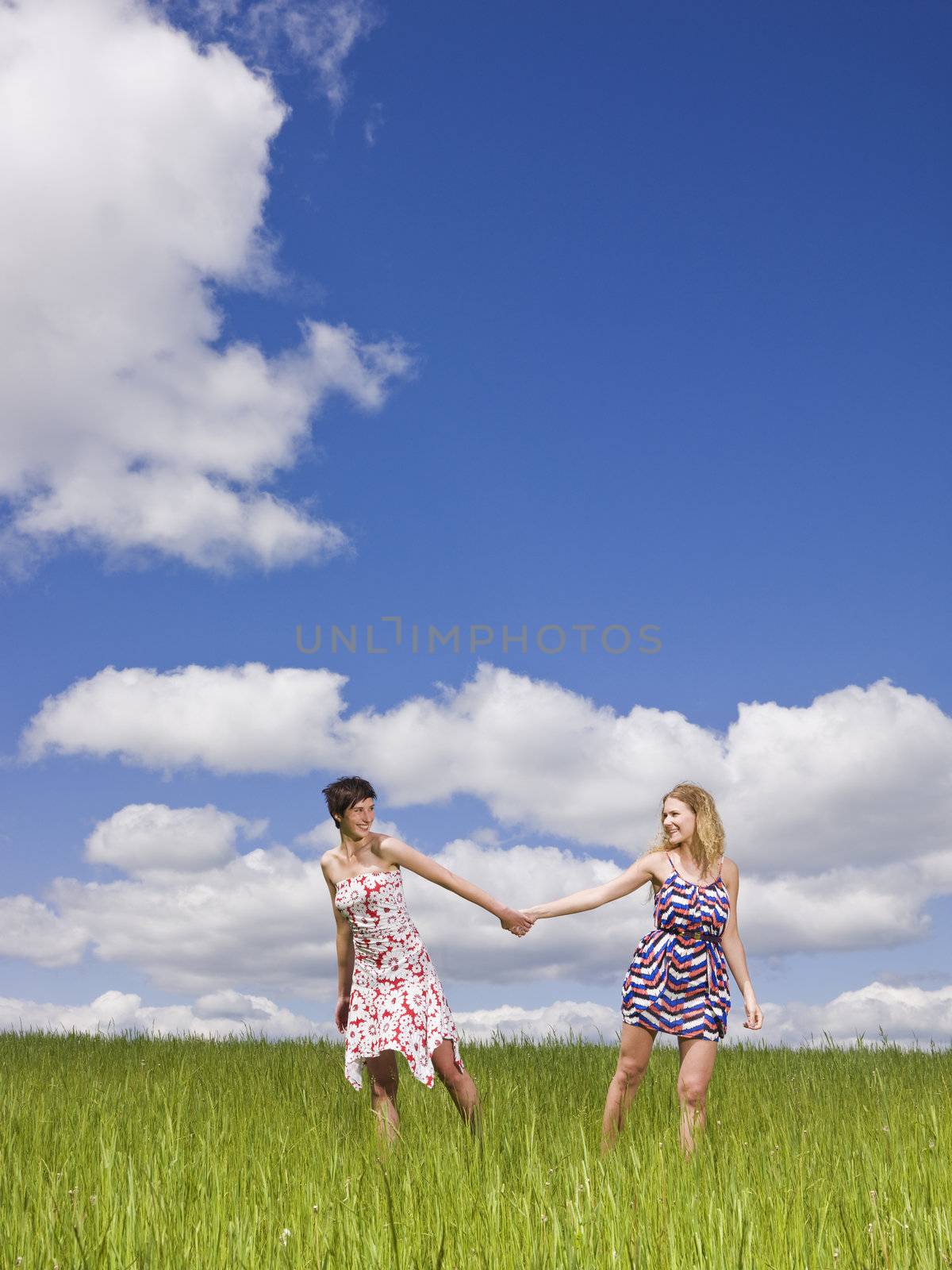 Two women holding hands on a field