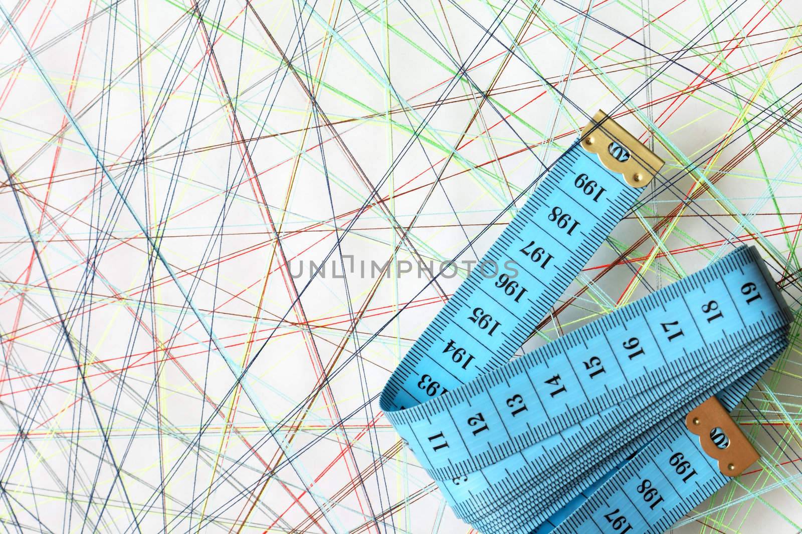 Blue tape measure on background with crossing colored threads