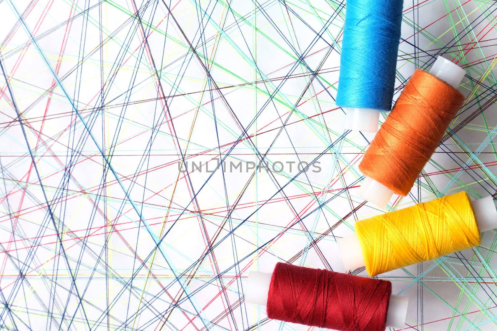 Four spools of thread on background with crossing threads