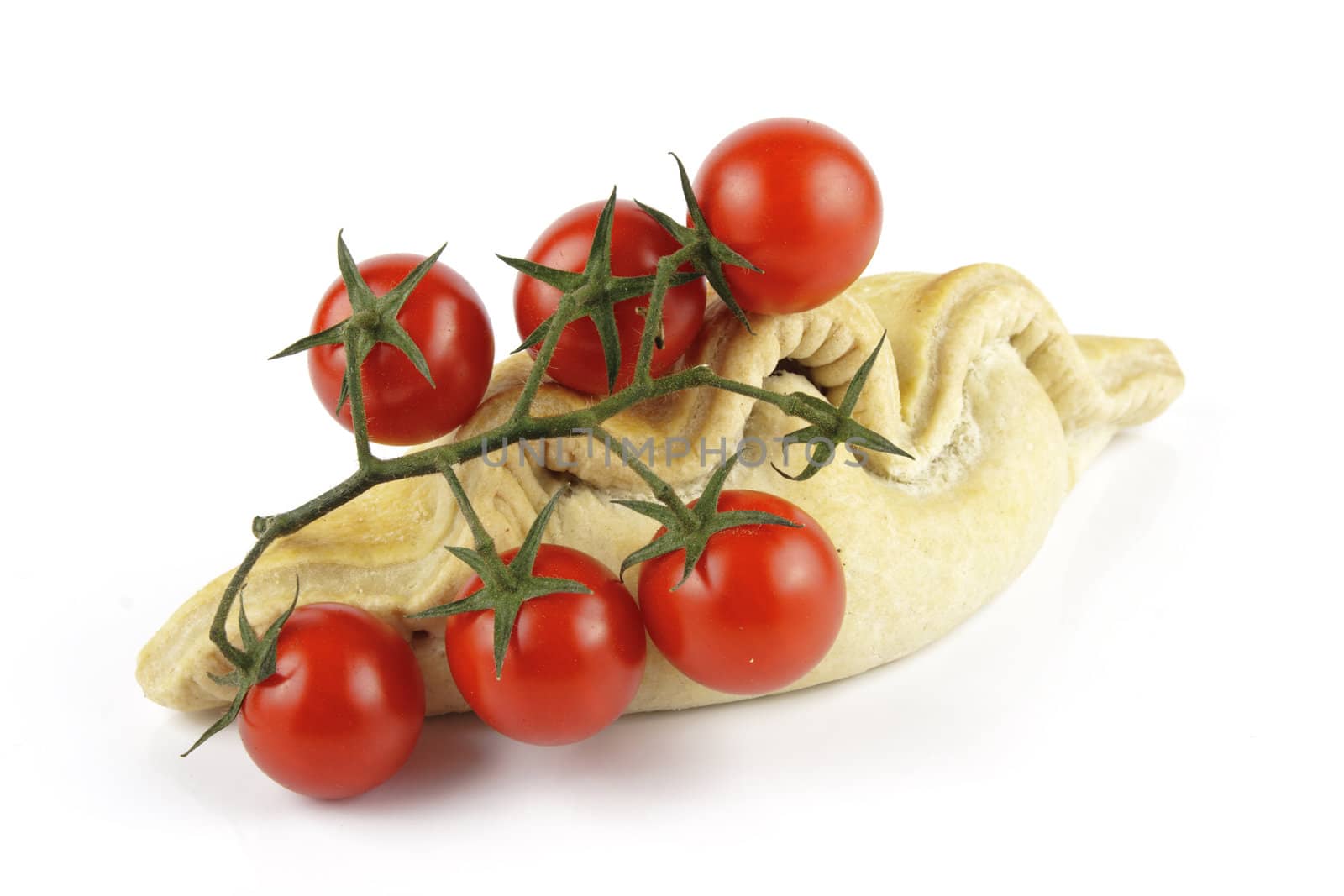 Contradiction between healthy food and junk food using tomatoes and a pasty on a reflective white background 