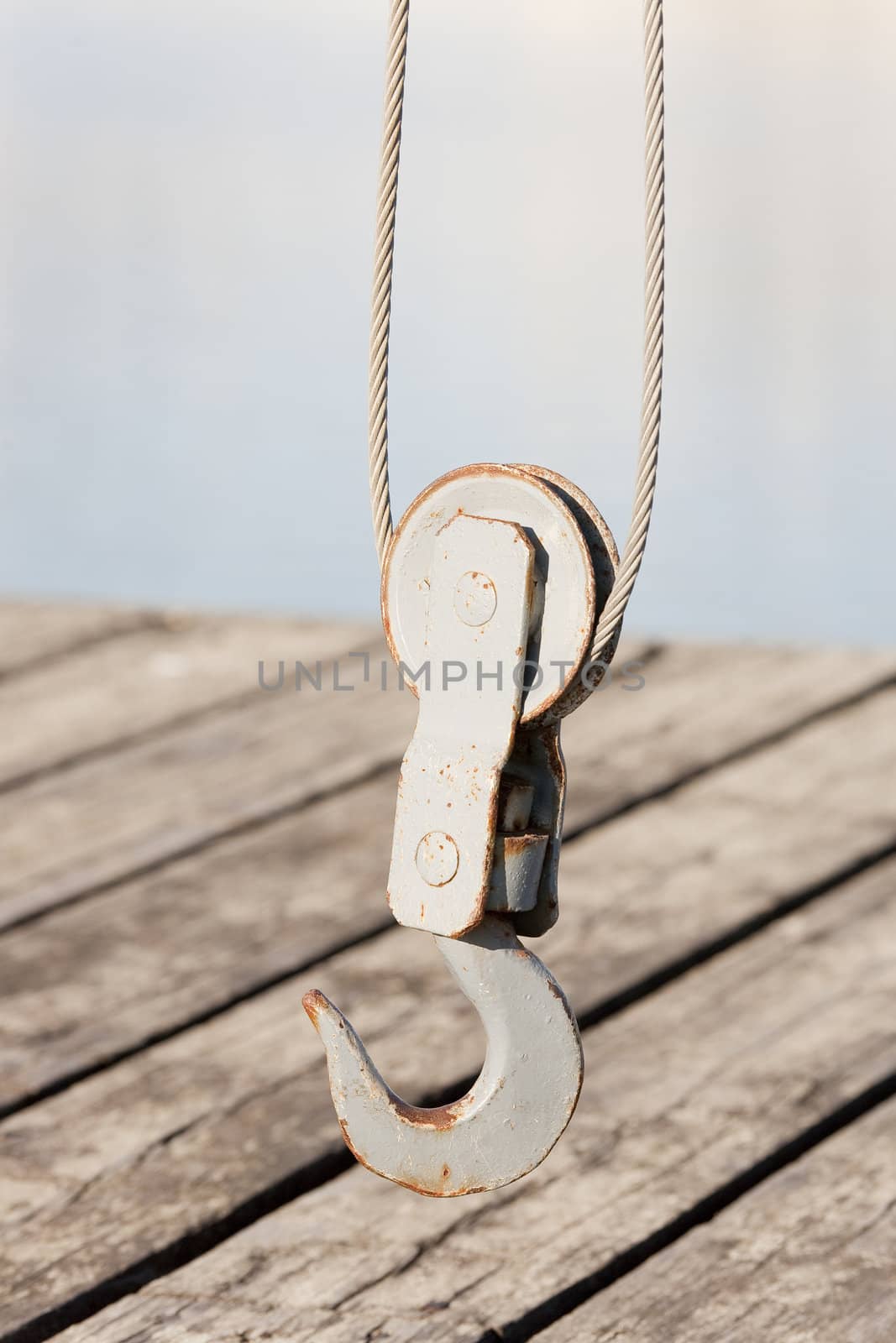 Closeup photo of a hook of a small mechanical crane on the dock.