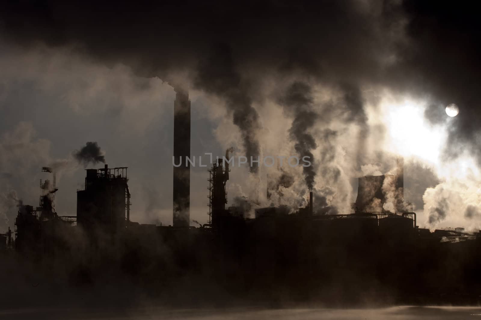 Paper mill covered by heavy smoke screen by hazy sunrise.