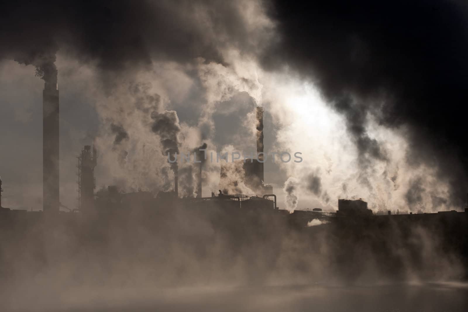 Paper mill covered by heavy smoke screen by hazy sunrise.