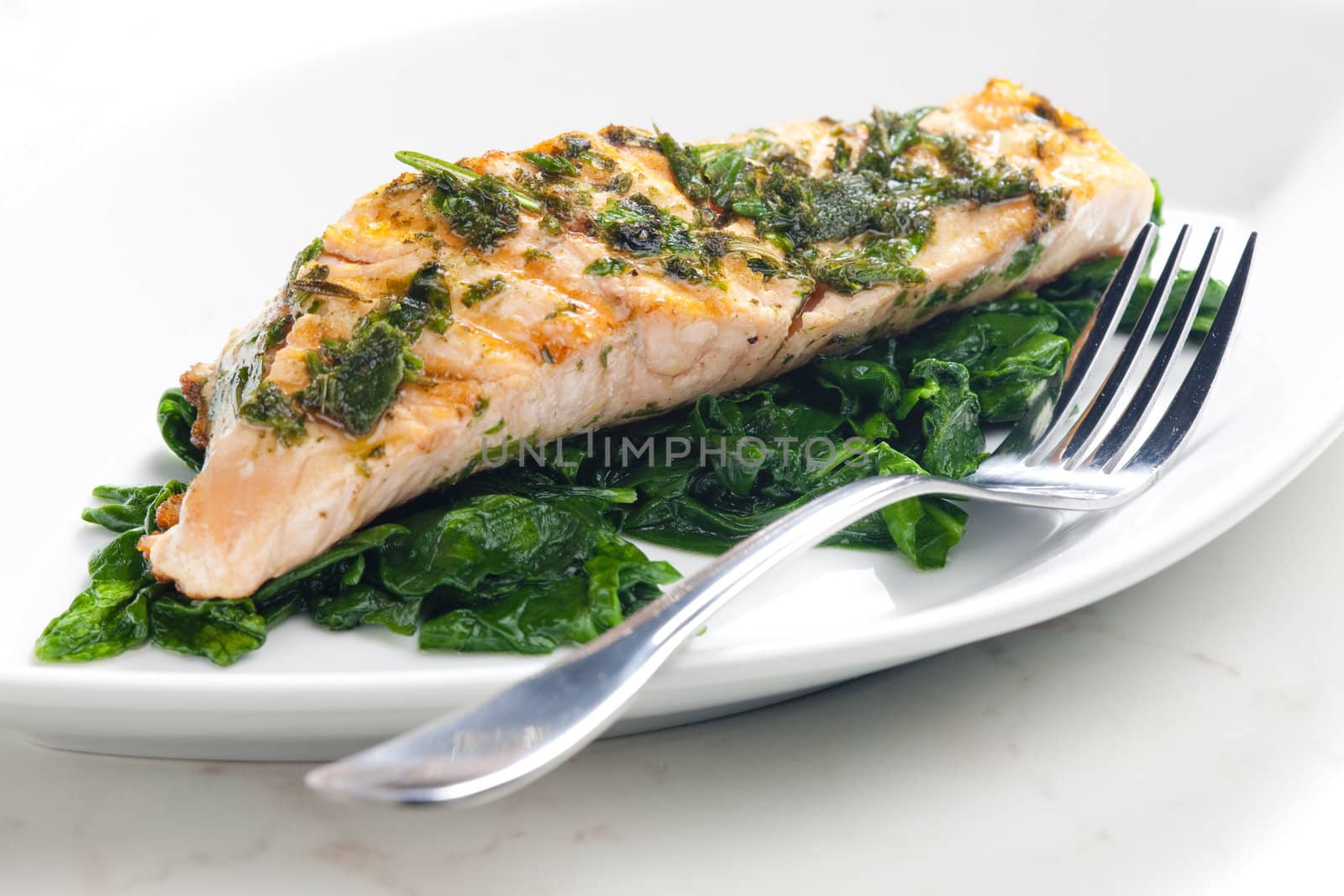 grilled salmon with herbs on fried spinach
