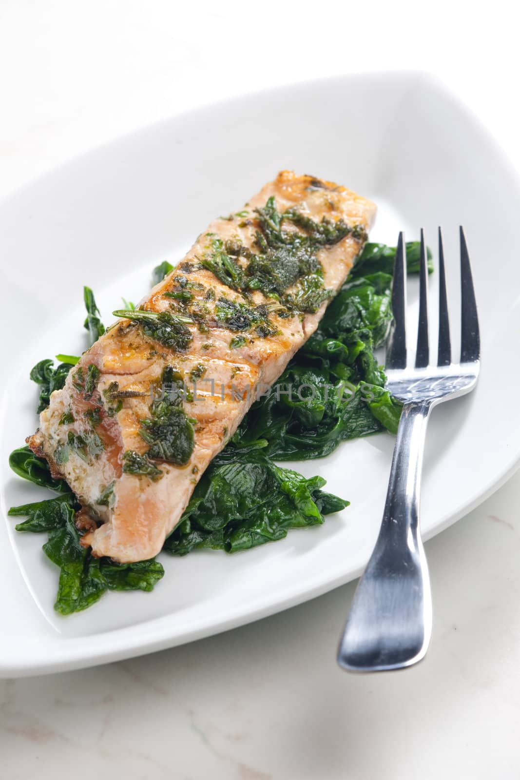 grilled salmon with herbs on fried spinach