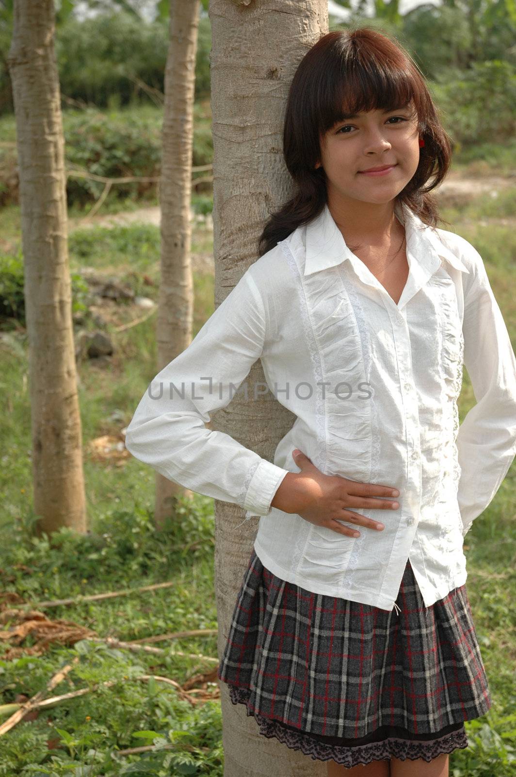 little asian girl stand up beside the tree in park