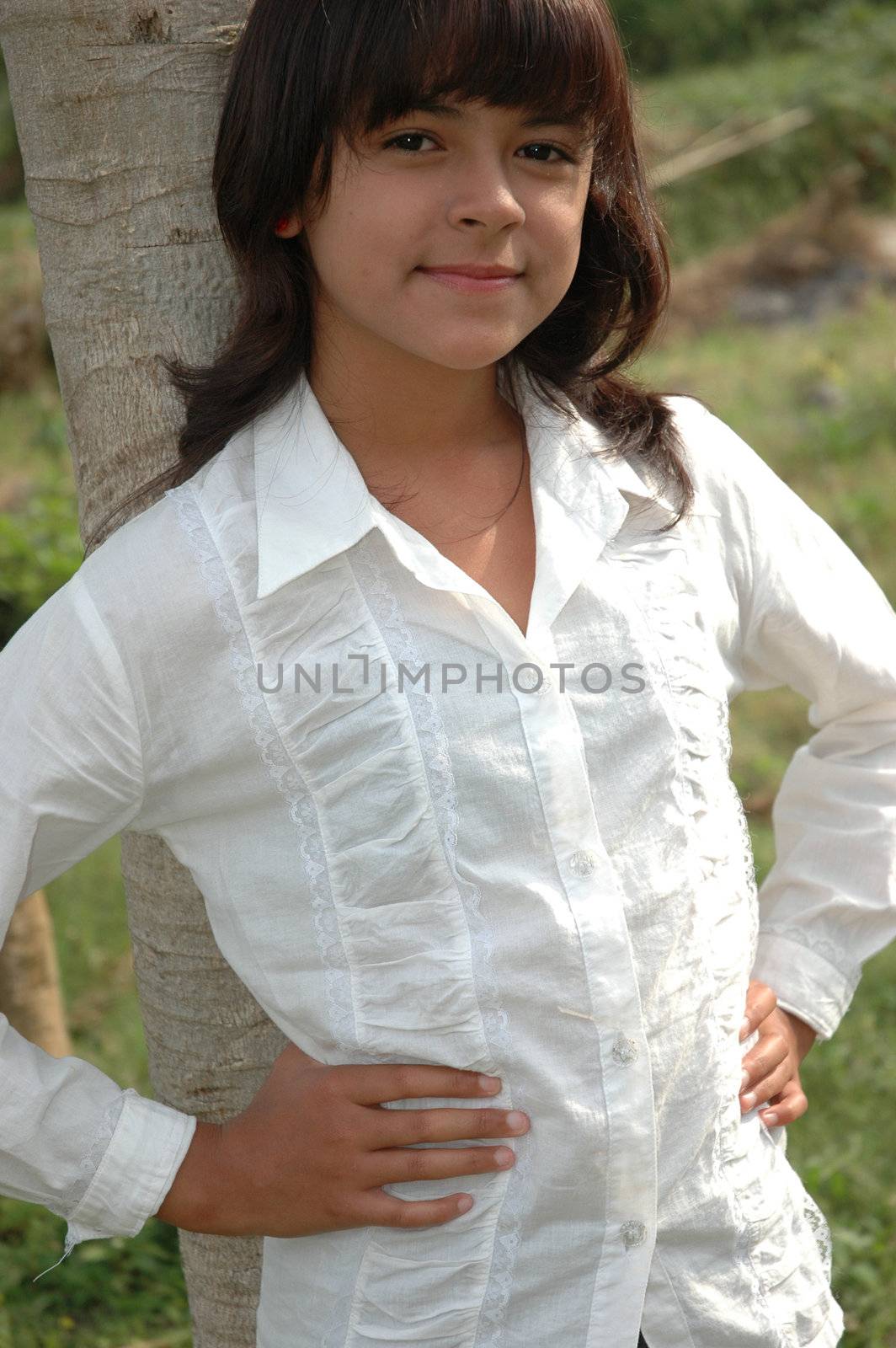 little asian girl stand up beside the tree in park