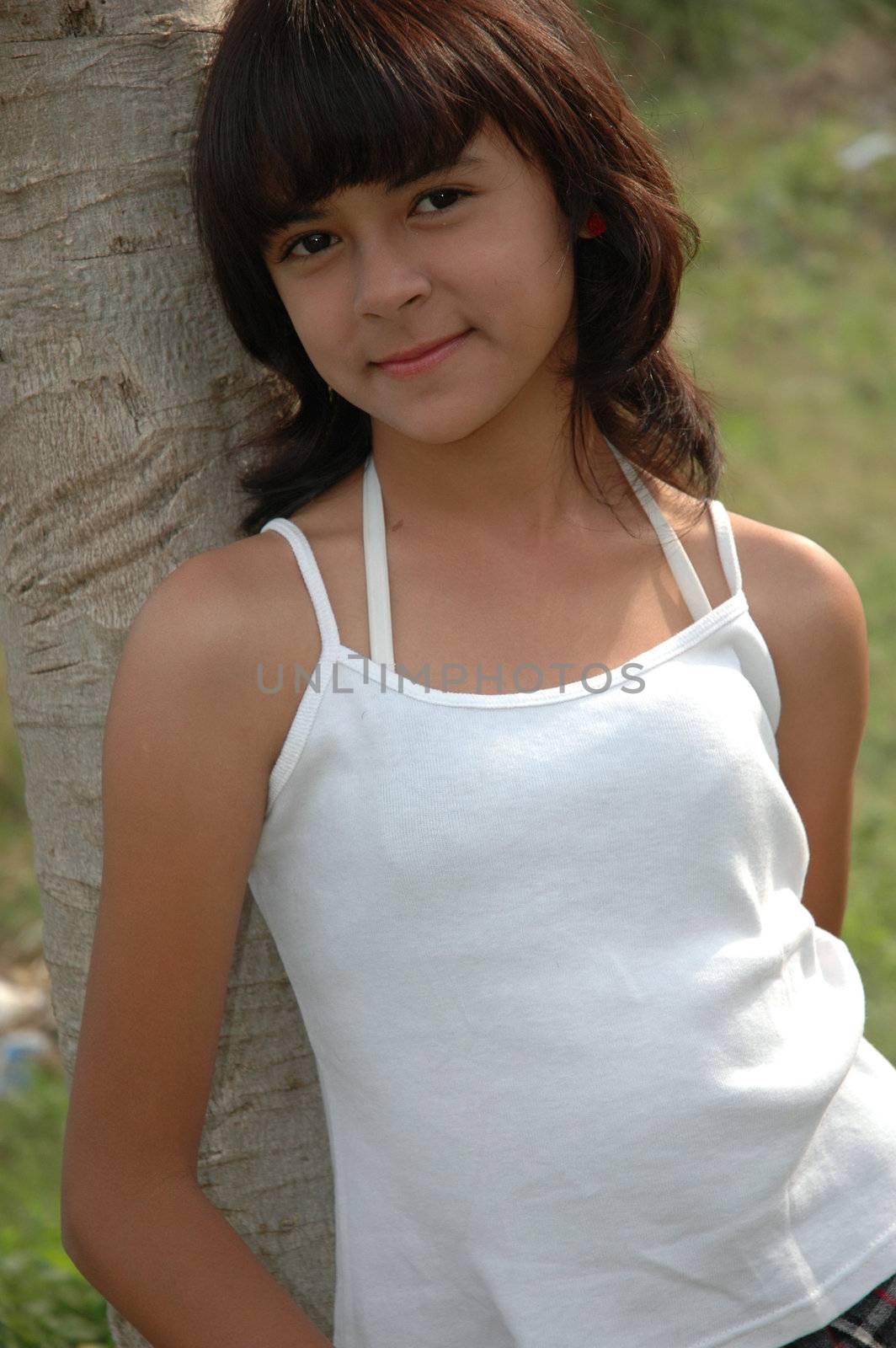 little asian girl stand up beside the tree in park