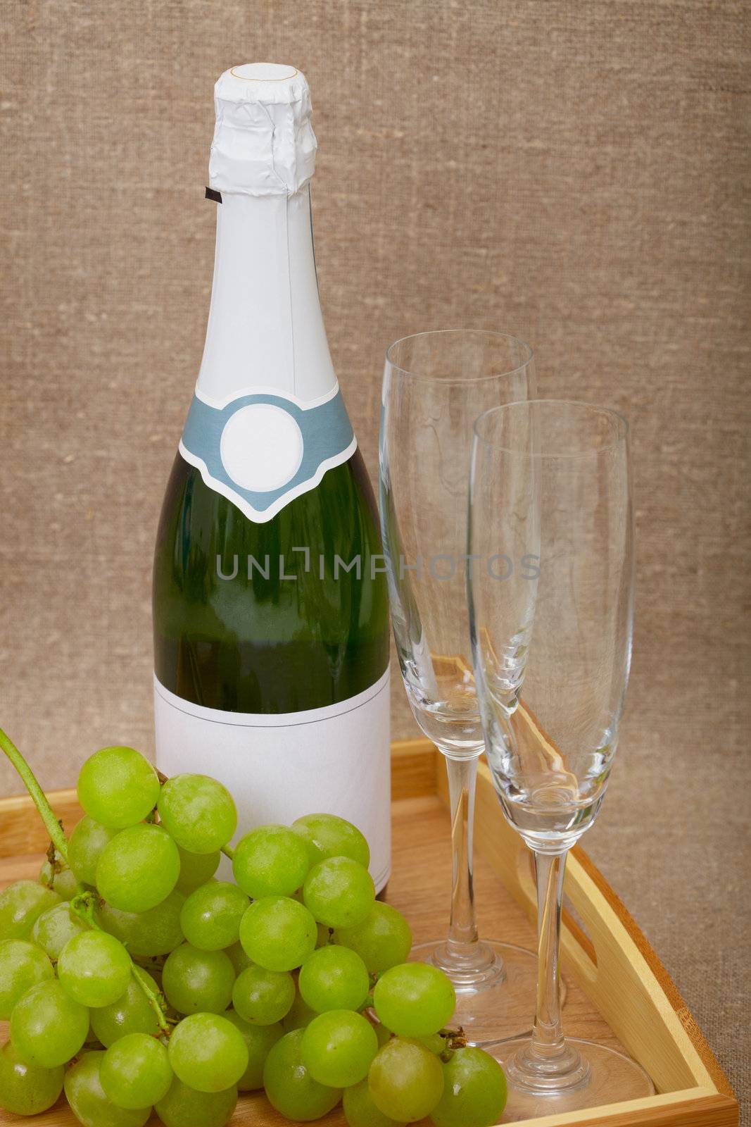 Bottle of sparkling wine with grapes and wine glasses