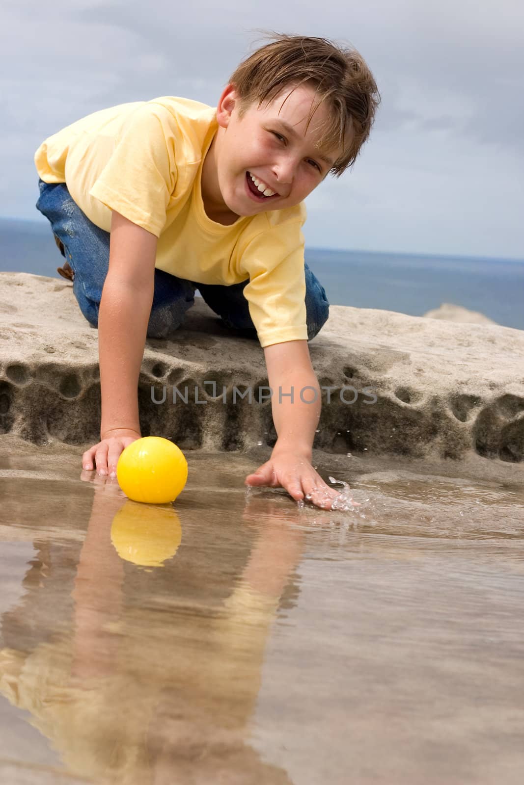 Happy child playing and splashing with yellow ball