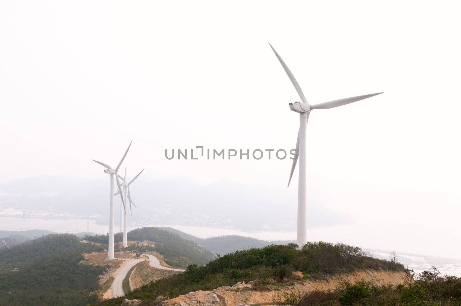 White electrical power generating wind turbines on rolling hills