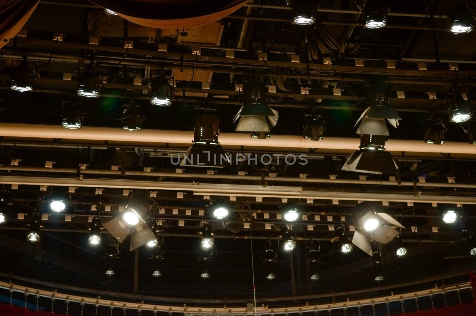 Multiple stage spotlight arrangement on ceiling of stage over black