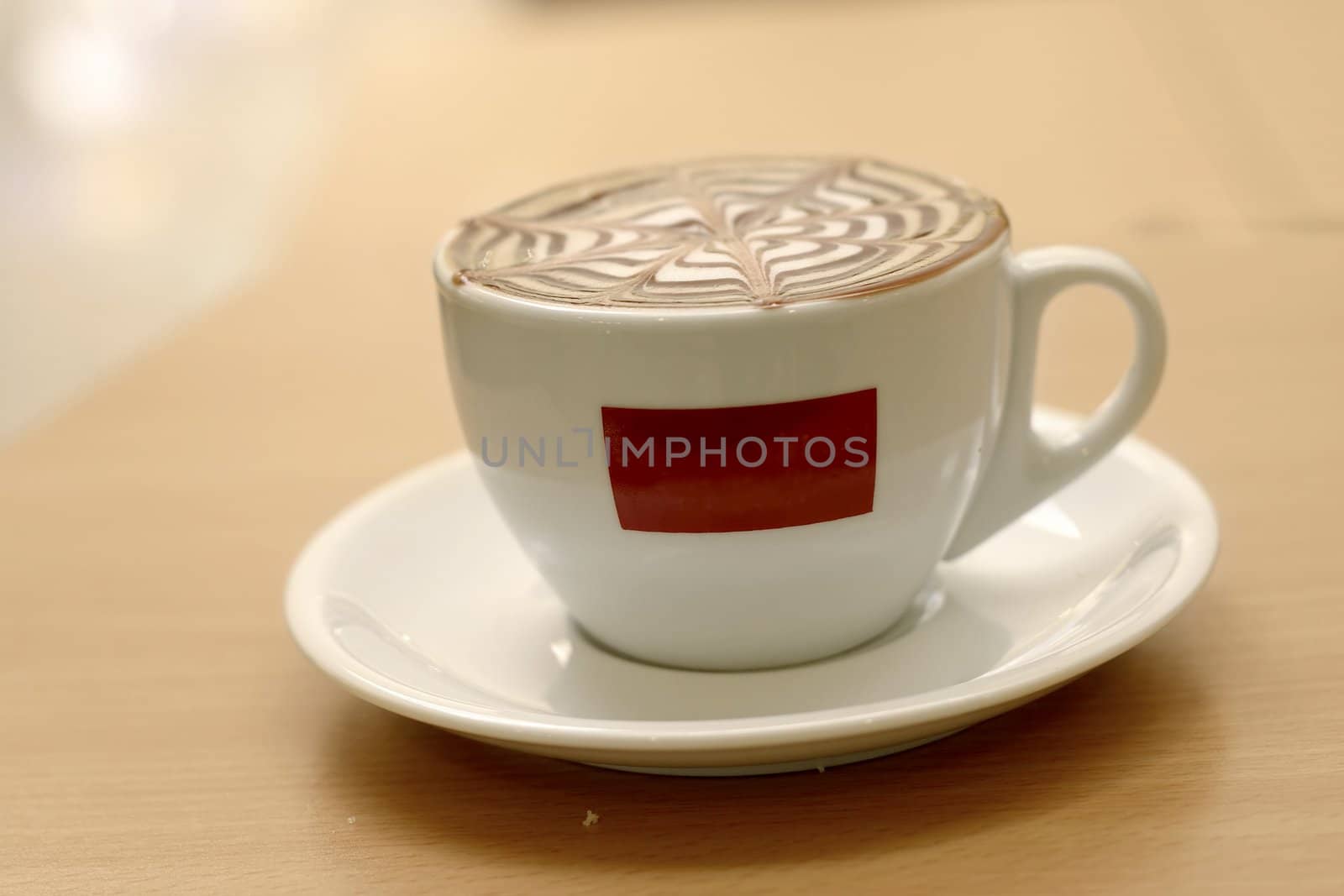 Mmmmm.  A delicious capuccino in a cafe - space for your logo or name as original was removed.  Focus on foreground cup . This image has a shallow dof.


