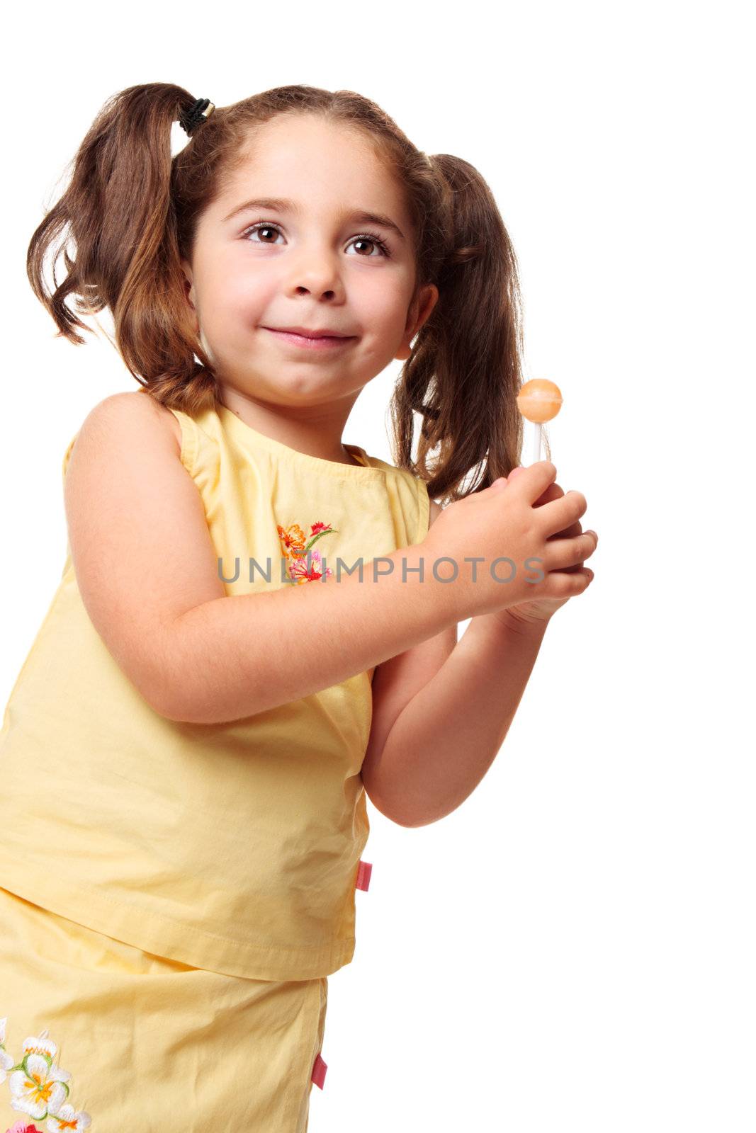 Little girl dressed in yellow is holding a sweet lolly
