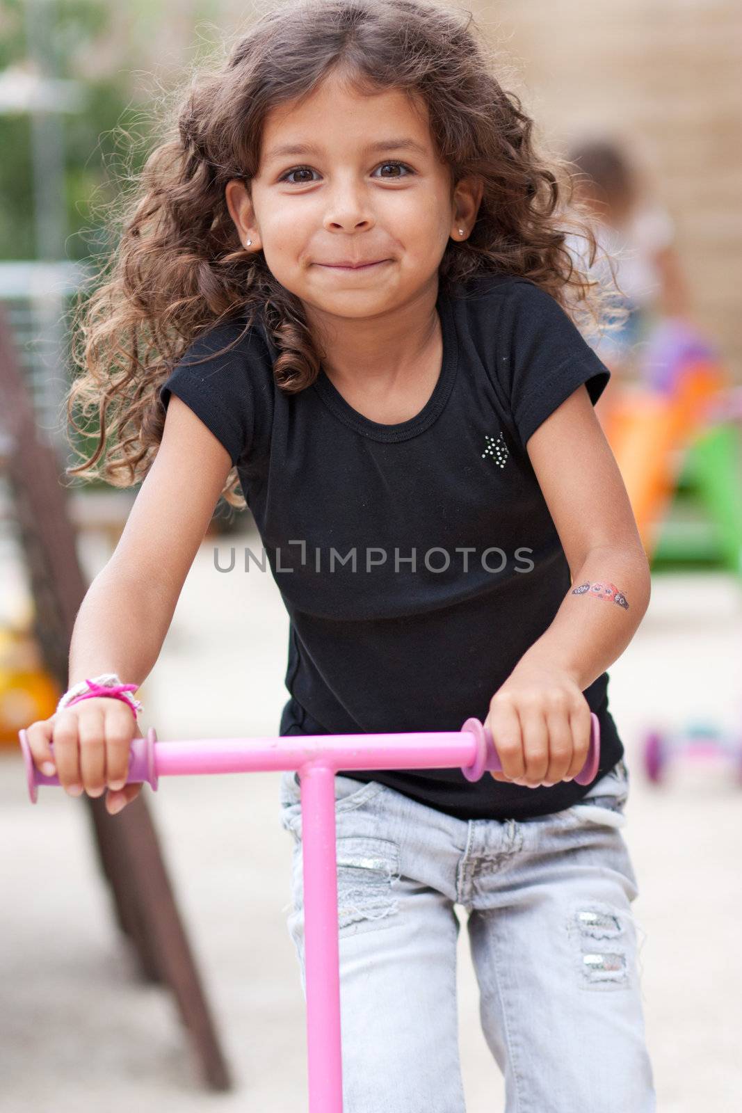 Smiling girl playing with a scooter 