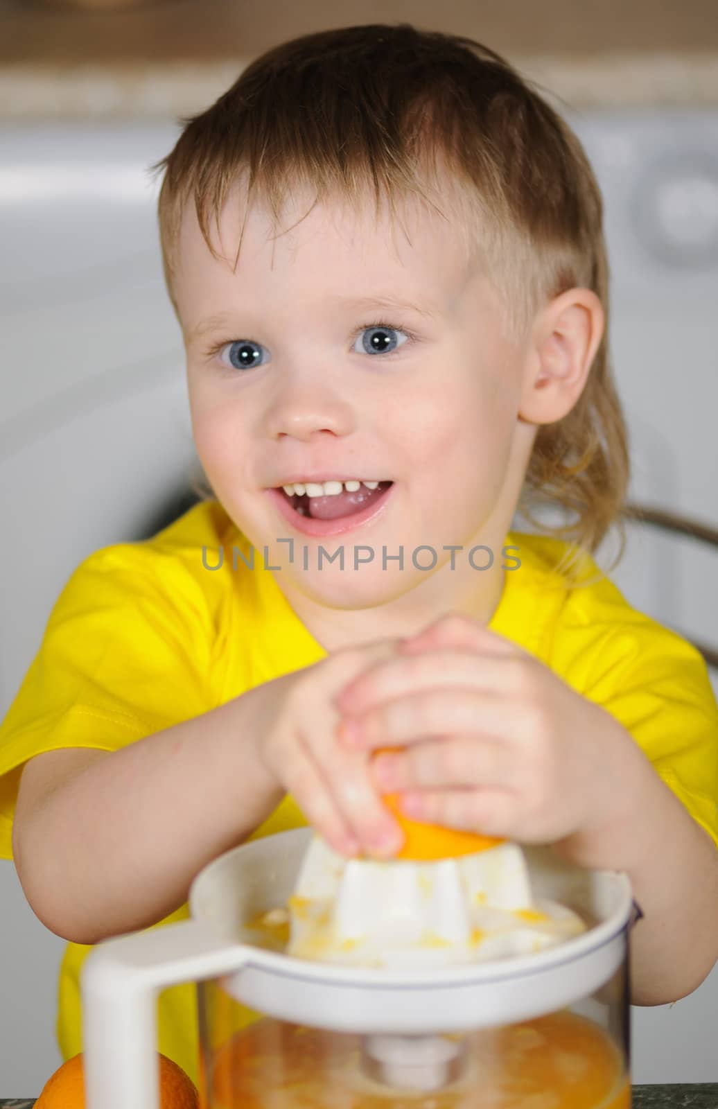 The child in a yellow vest to wring out juice  from an orange