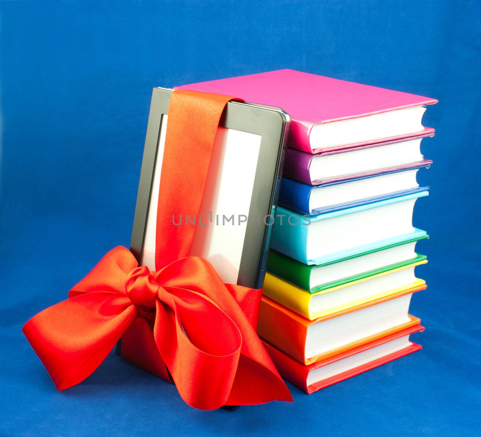 Electronic book reader tied up with red ribbon and stack of books