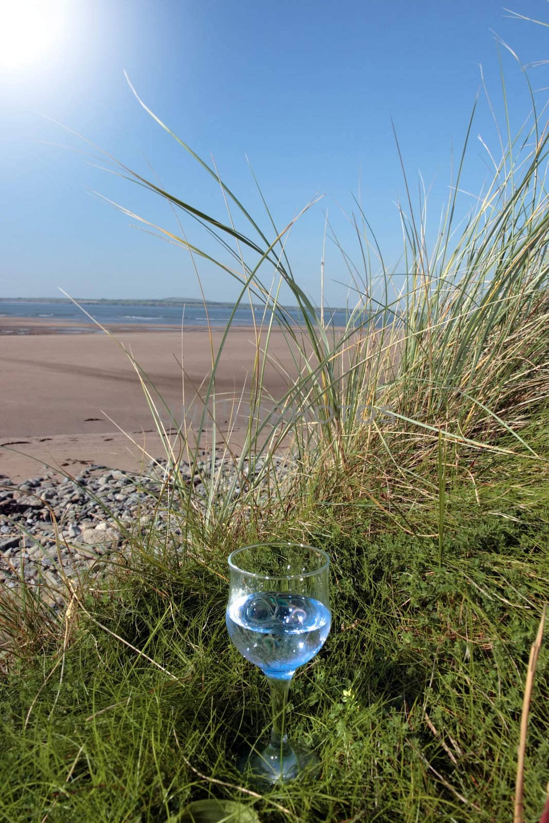 single glass of pure natural water standing on the beach dunes in kerry ireland