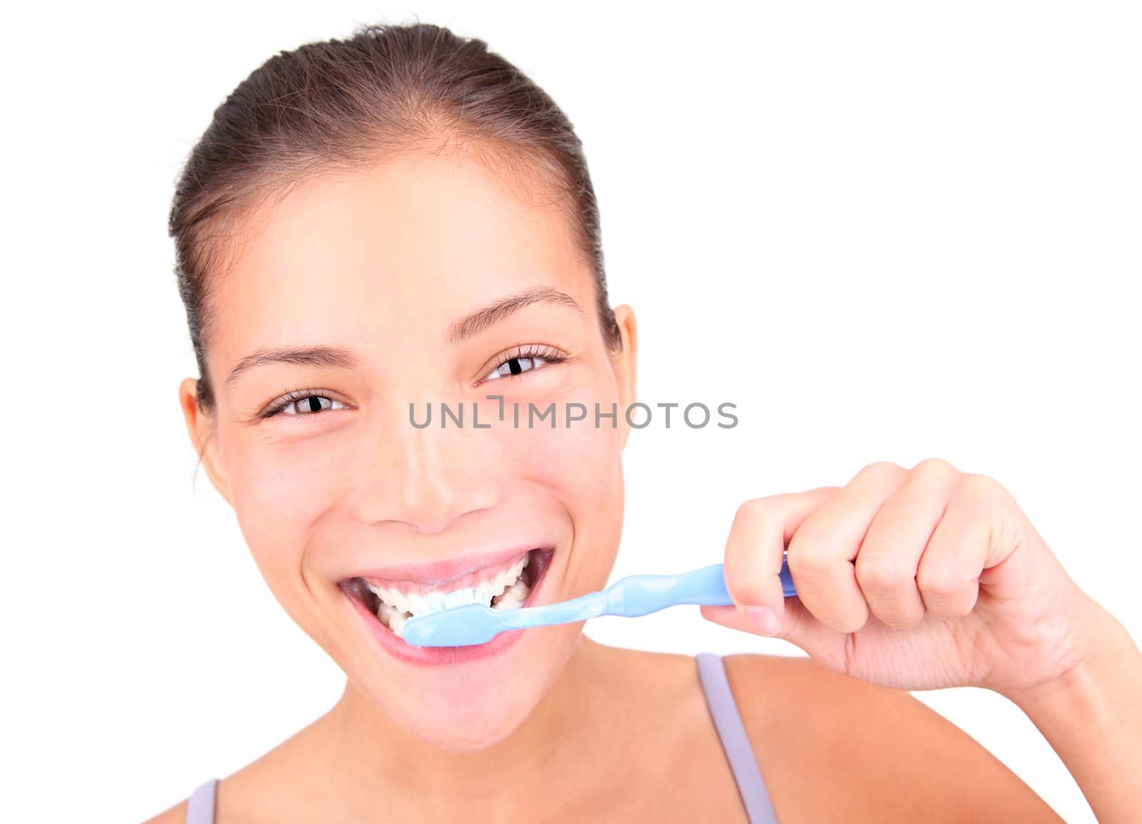 Brushing teeth. Closeup of woman actually brushing her teeth with toothpaste and a manual toothbrush. Beautiful mixed race asian / caucasian model.