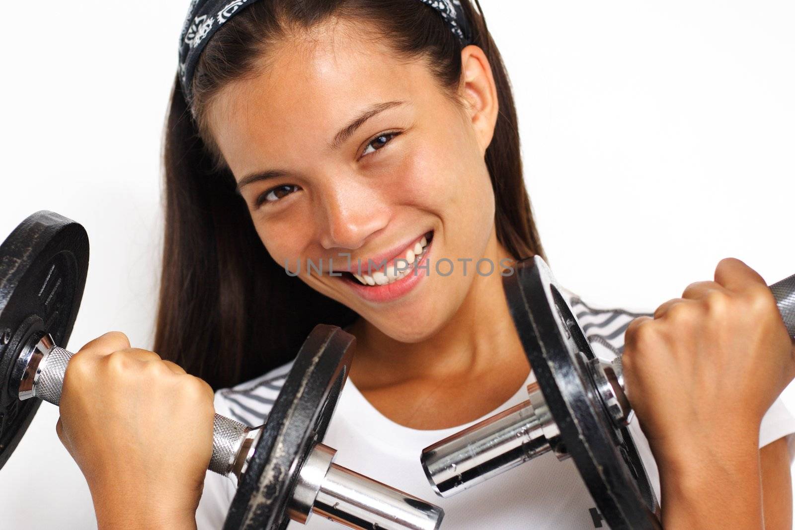 Attractive woman lifting weights and smiling at the camera. Closeup.