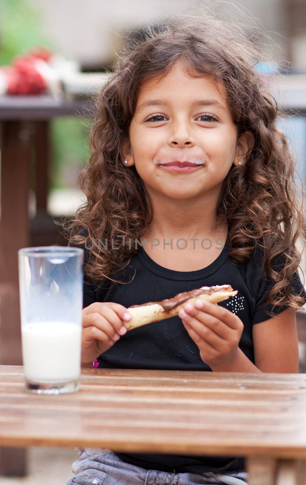 Girl eating a slice of bread and drinking a glass of milk