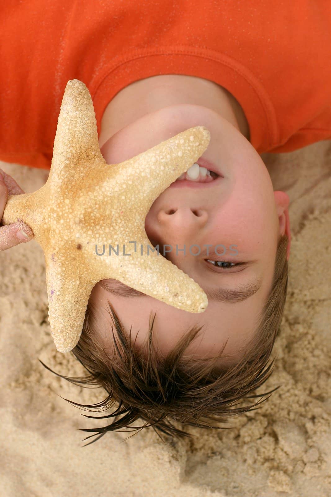 Funny child, holding a starfish at the beach - closeup.