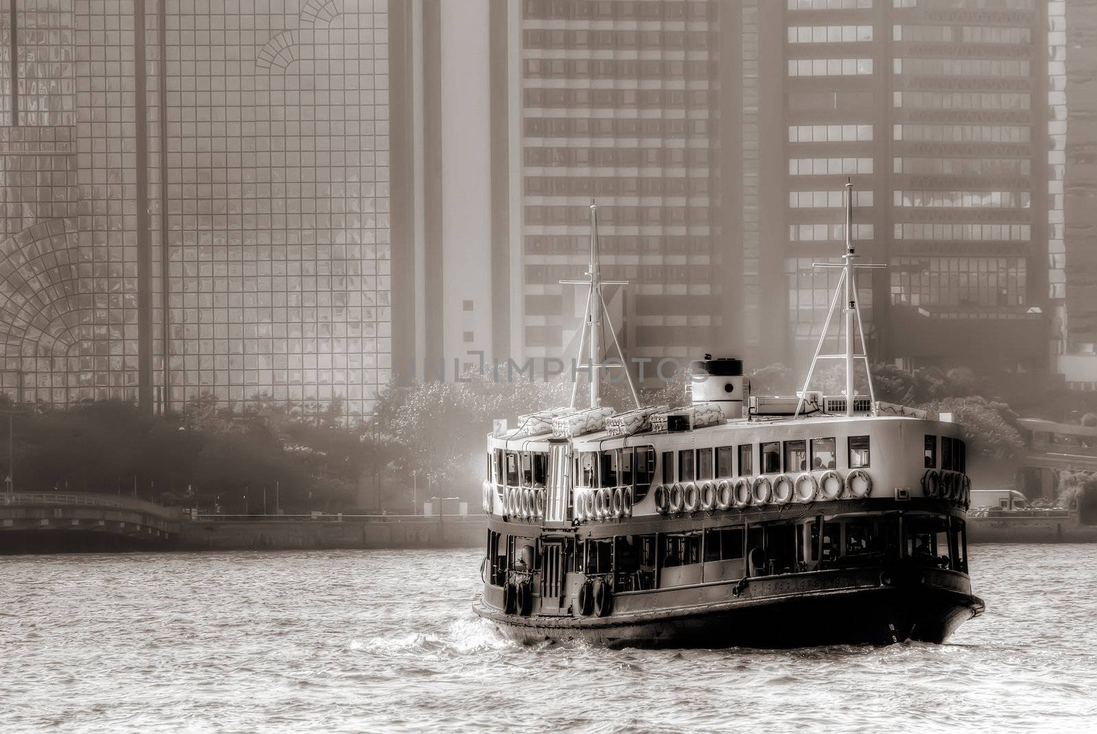 Boat on Victoria harbour in Hongkong with tall buildings.