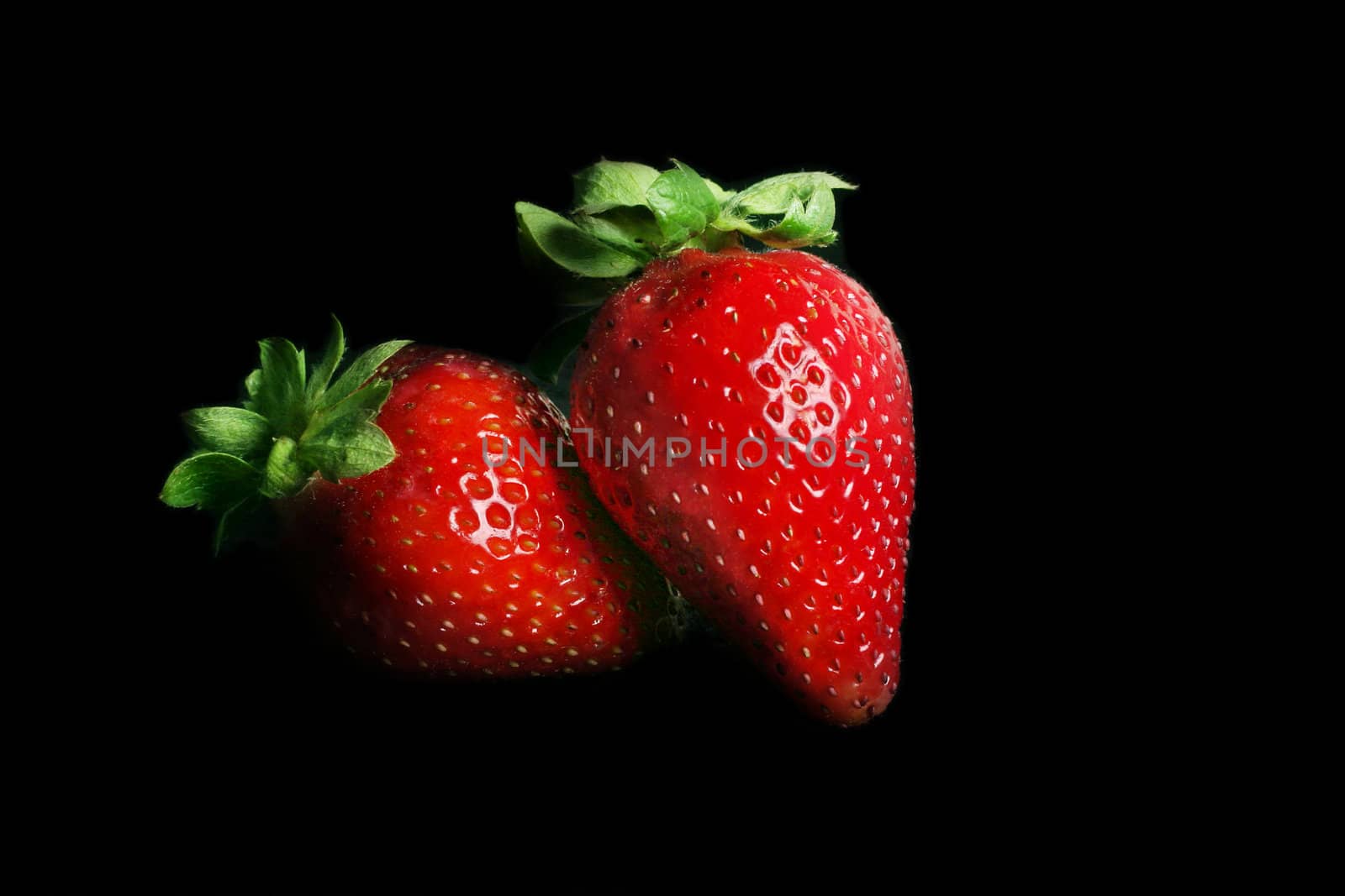 Two ripe strawberries on black
