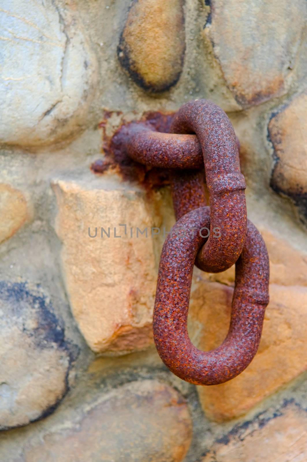 Rusty chain hanging on old stone wall
