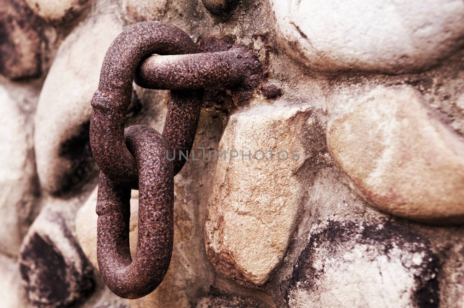 Rusty chain hanging on old stone wall
