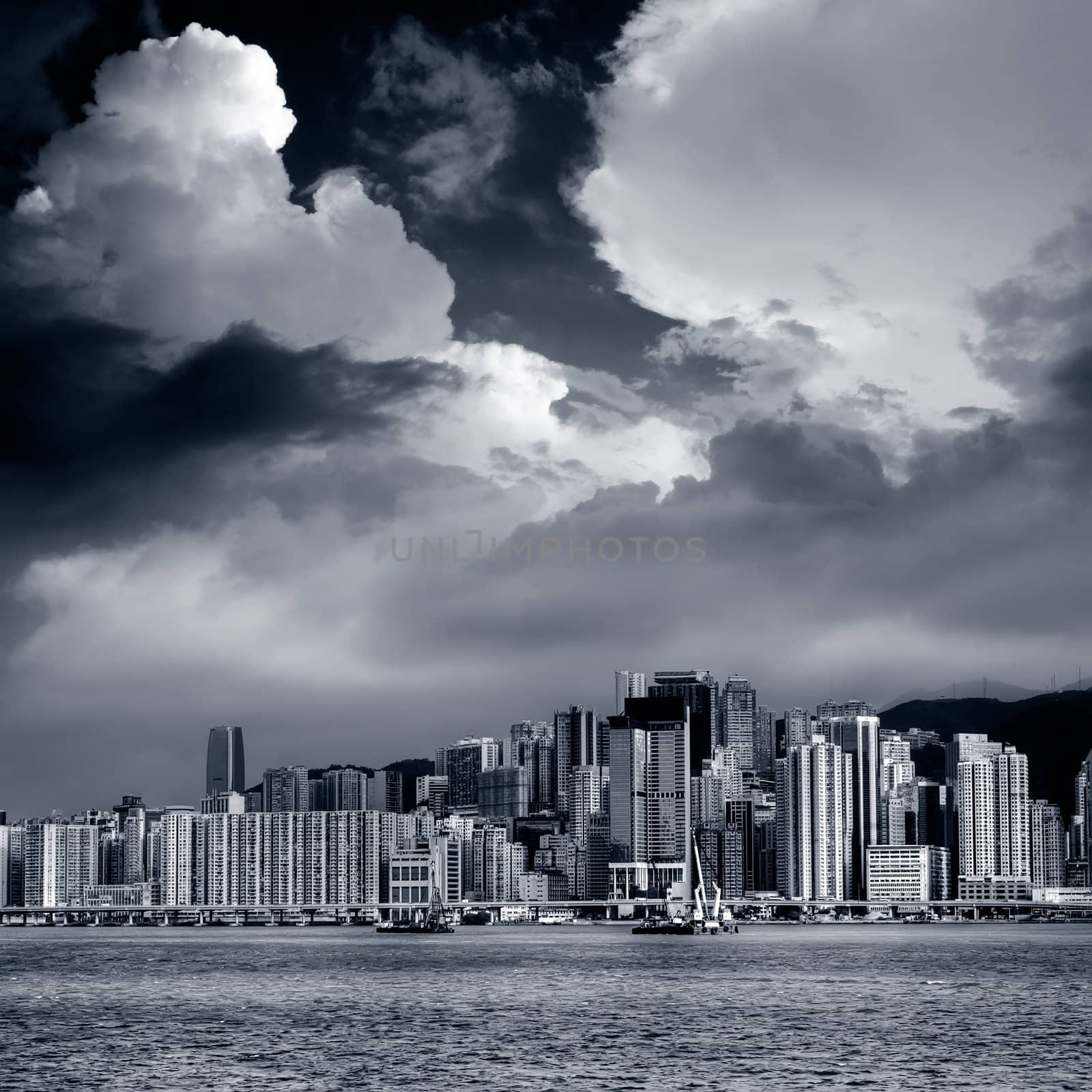 Skyscraper near the sea with dramatic sky in Victoria Harbor, Hong Kong.