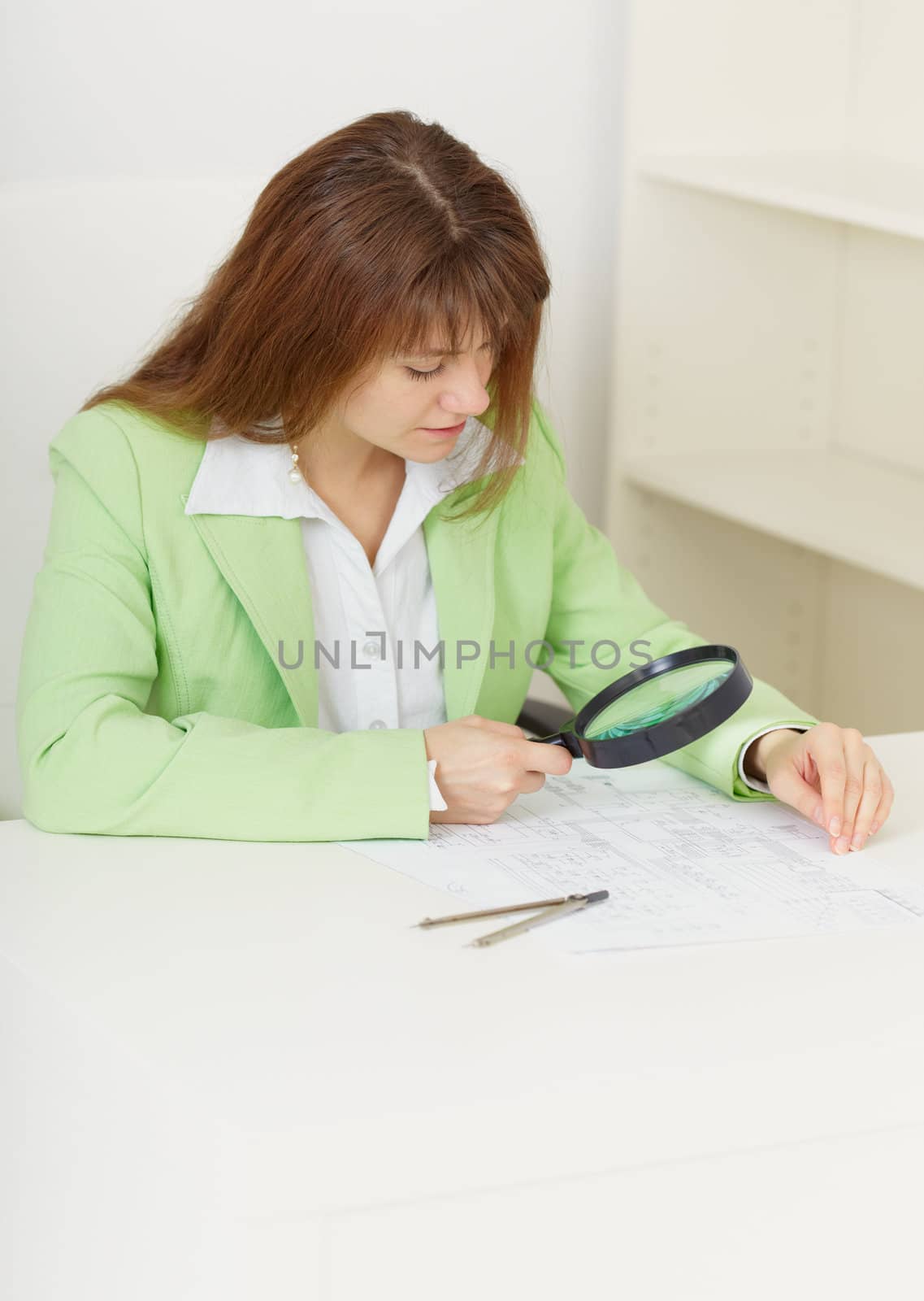 The young woman works with drawings by means of a magnifier