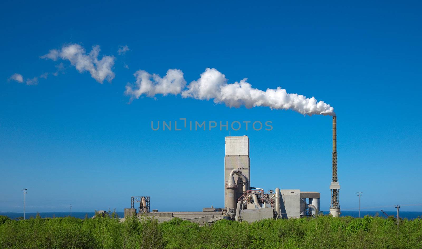 A photography of a cement plant under a blue sky