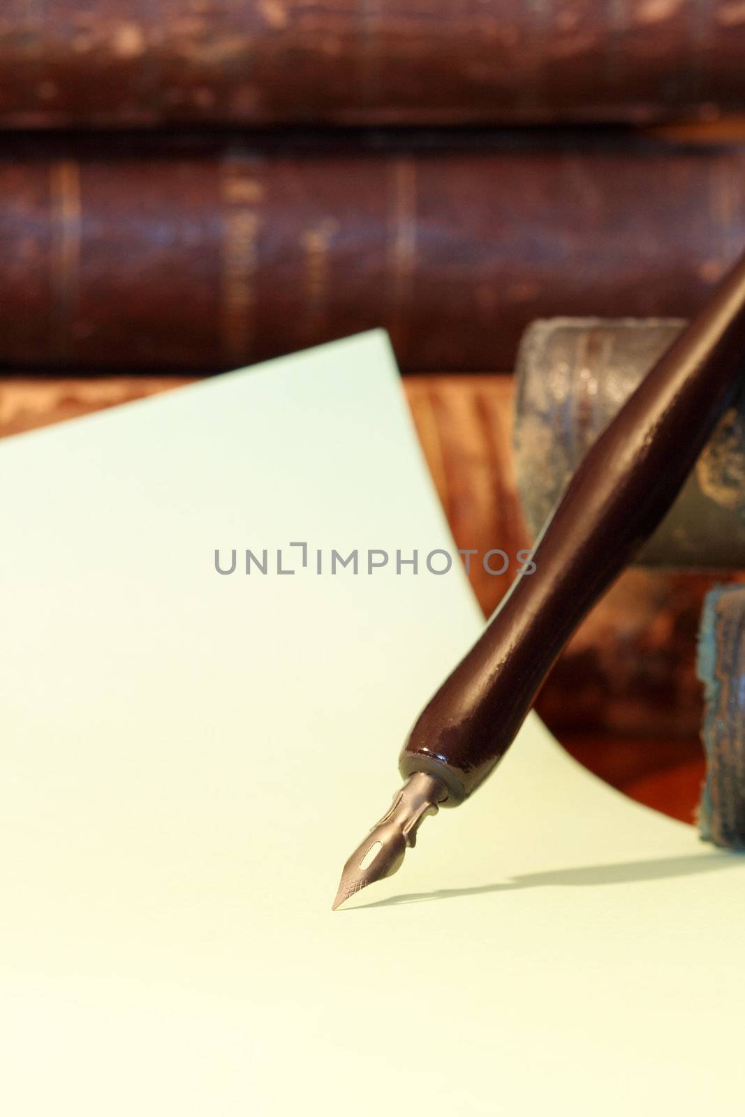 Ancient fountain pen on vintage background with paper sheet and old books